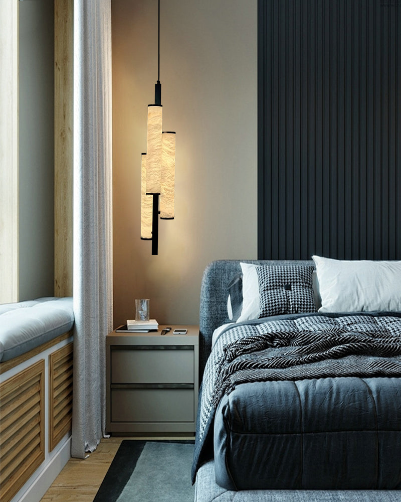 Stylish alabaster pendant lamp illuminating a modern bedroom with layered textiles.