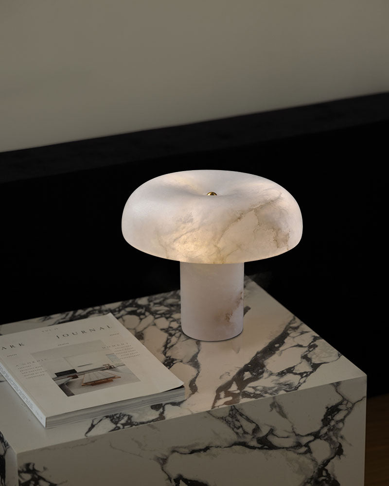 White marble stone table lamp with a rounded silhouette on a marble table.