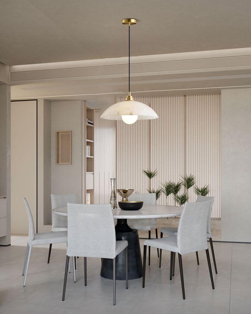 Natural stone pendant light above round black dining table with white chairs.