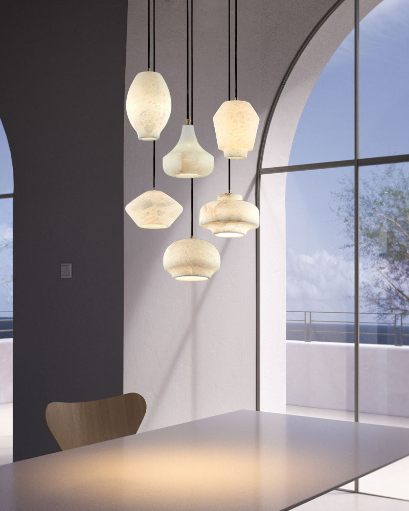 Collection of stylish alabaster pendant lamps above a modern white dining table.