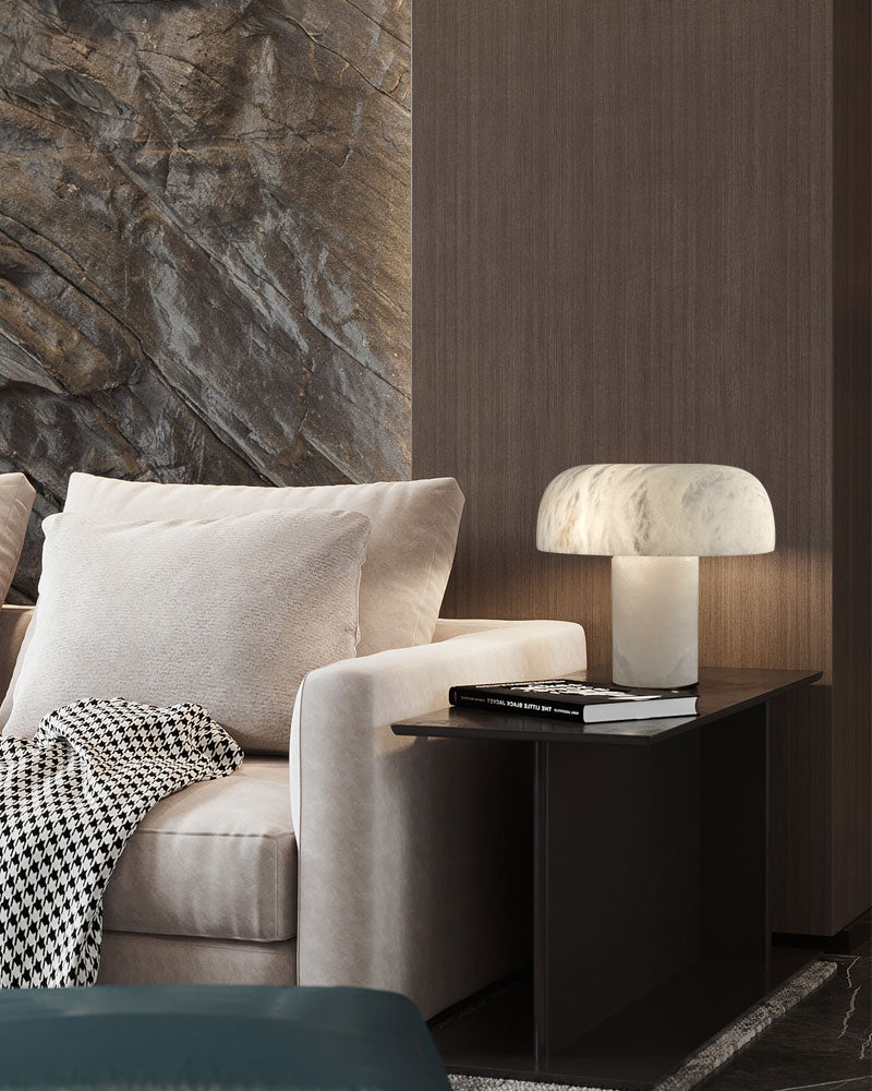 Elegant white marble table lamp on black side table beside a plush beige sofa.