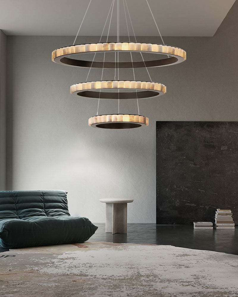 Triple chandelier lamp with alabaster rings above minimalist seating area.