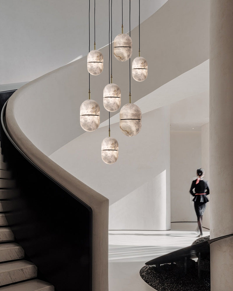 Minimalist alabaster pendant lights hanging over a curved staircase in a modern home.