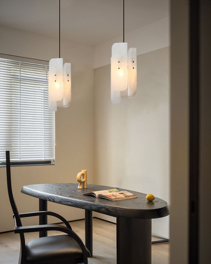 Modern dining setup with a black marble table and alabaster pendant lighting.