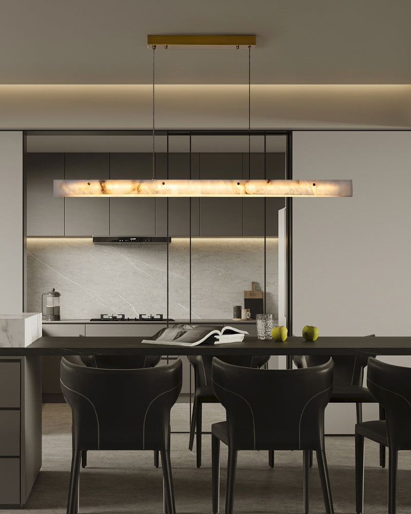 Sleek marble pendant light above modern dining table with black chairs in a stylish kitchen.