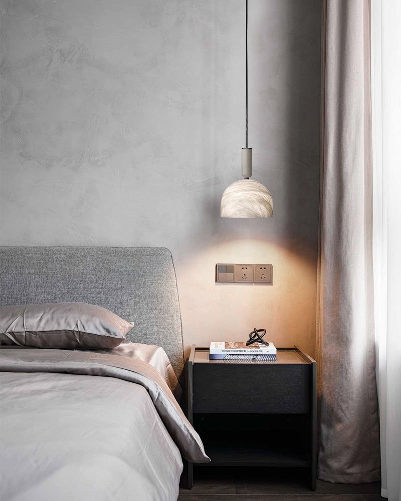 Postmodern white marble pendant light above a stylish bed in a minimalist bedroom.