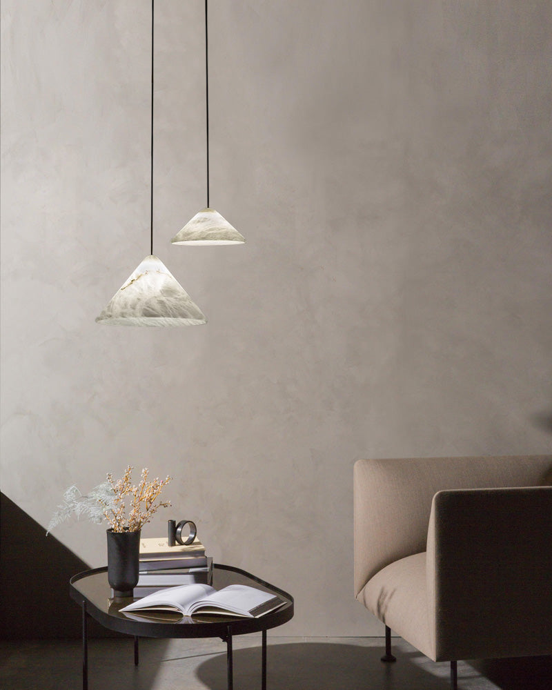 Alabaster pendant lamps casting warm light over a minimalist living space with a brown sofa.