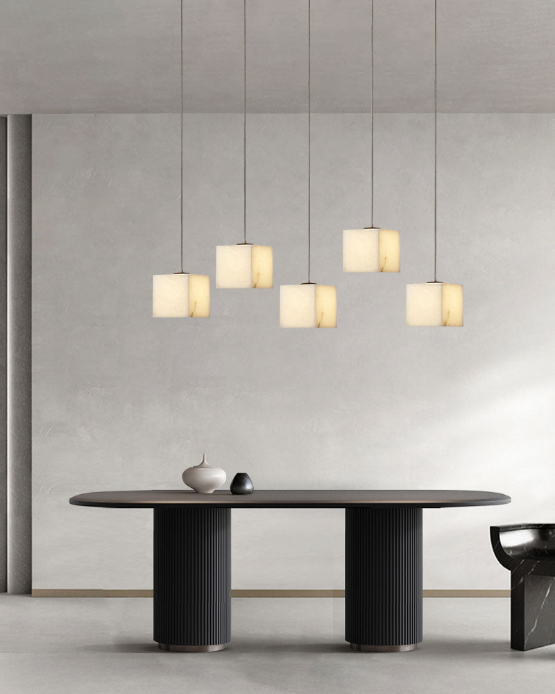 Group of five square white alabaster pendant lights over a sleek modern dining table.