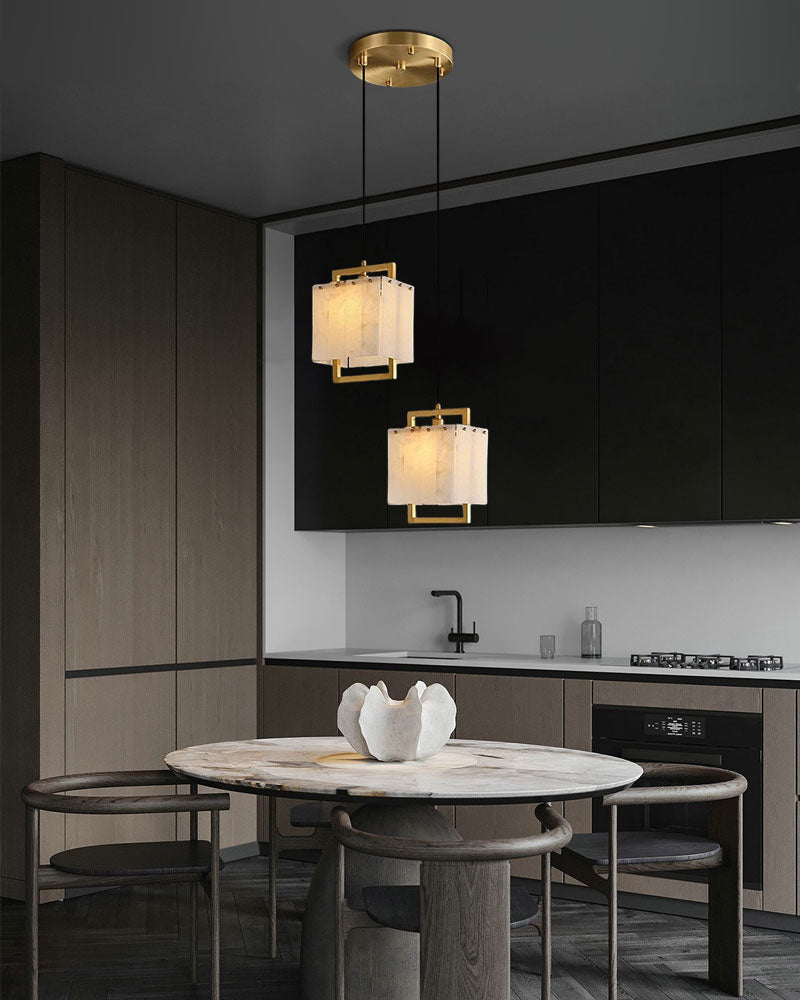 Gold and marble pendant lamps above round marble dining table in modern kitchen.