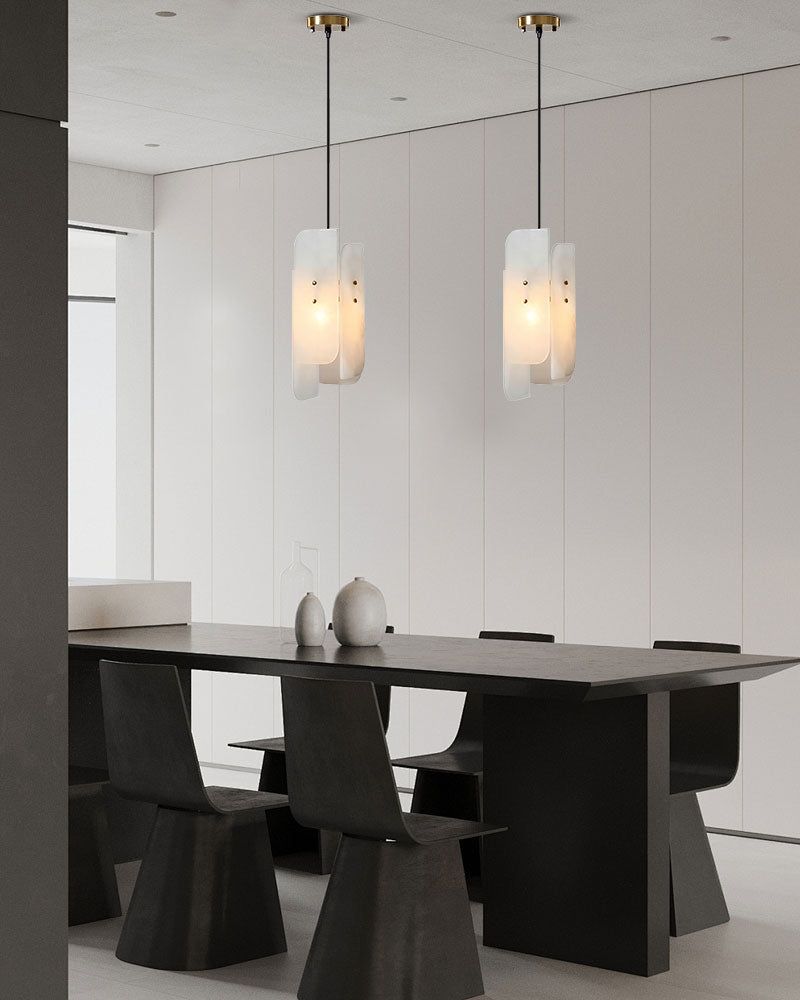 Modern black dining table with alabaster pendant lights in minimalist space.