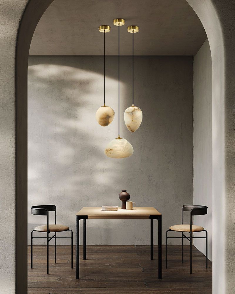 Dining space with three G9 Alabaster Pebble pendant lights above a wooden table.