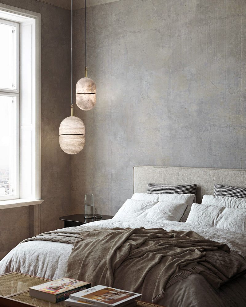 Minimalist alabaster pendant lights above a cozy modern bedroom with textured walls.