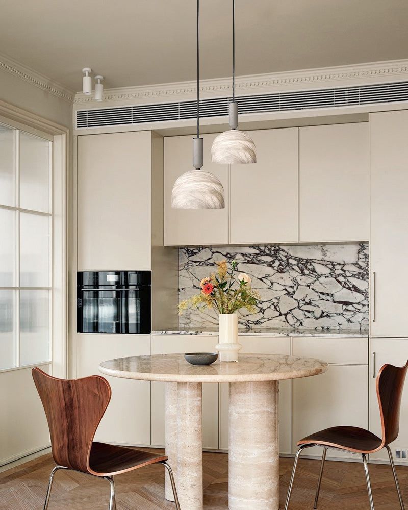 Elegant white marble pendant lights illuminating a contemporary kitchen dining area.