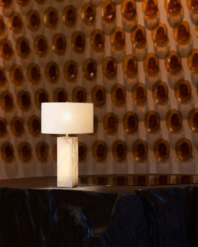 Vintage alabaster marble table lamp with white fabric shade on dark table.