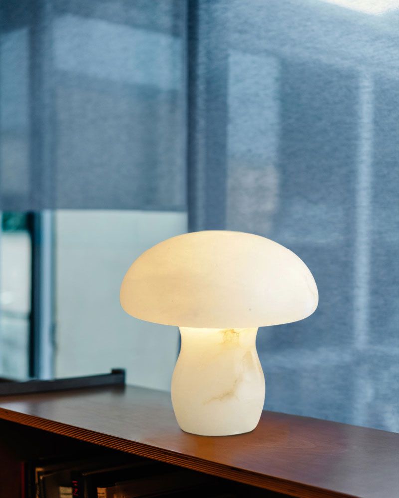 Mushroom-shaped lamp on wooden shelf, emitting warm glow in a modern interior.