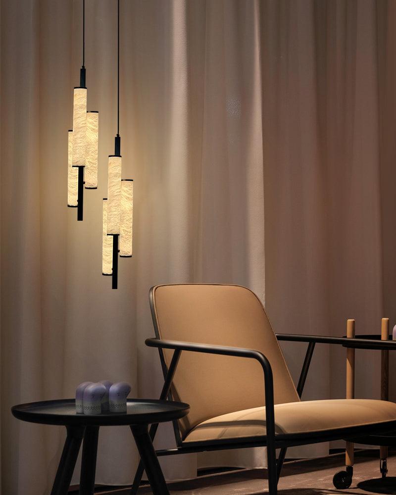 Elegant alabaster pendant lights above a modern chair and side table in a cozy setting