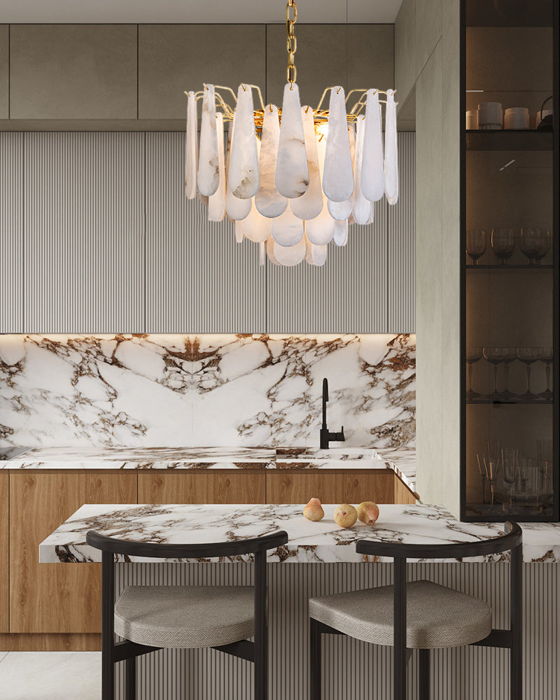 Tiered raindrop chandelier illuminating modern kitchen with marble island and cabinetry