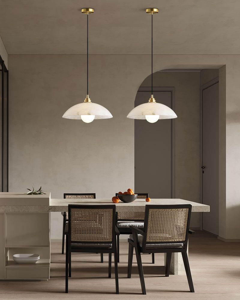 Natural stone pendant lamps over modern dining table with black chairs and decor.