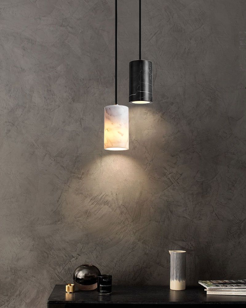Sleek black and marble pendant lamps lighting a stylish tabletop against textured wall.