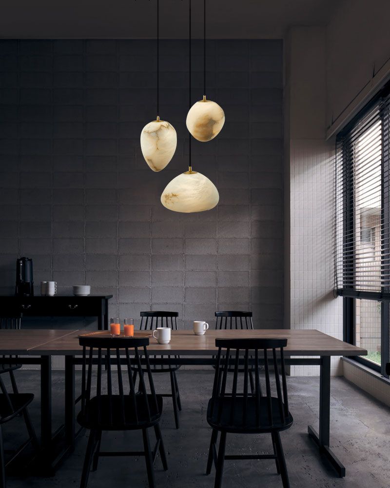 G9 Alabaster pendant lights above modern dining table with black chairs and decor.