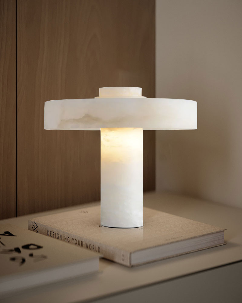 Elegant E27 round alabaster lamp glowing on a minimalist surface with books.