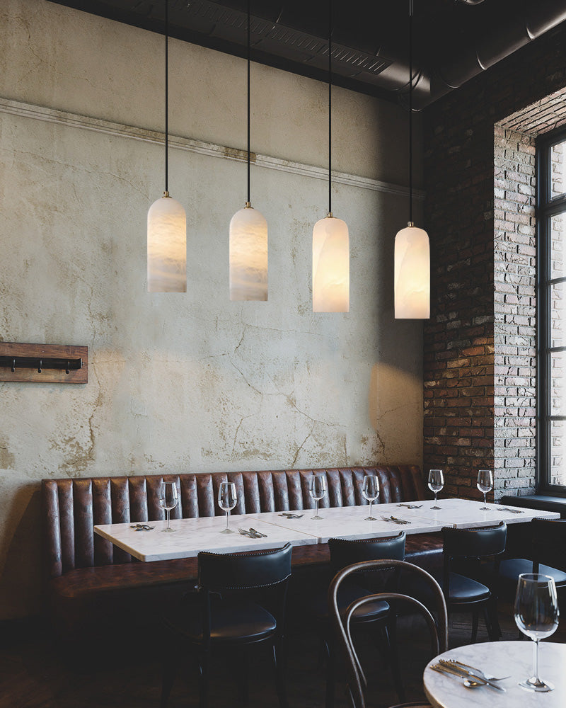 Modern restaurant interior with marble table and four minimalist pendant lights.