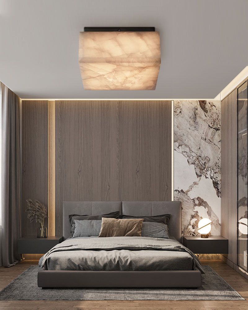 Square alabaster ceiling light illuminating modern bedroom with neutral tones.