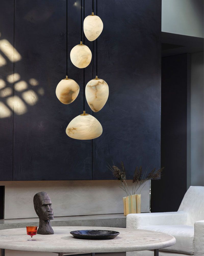 G9 Nature Alabaster Pebble pendant lights hanging above a round table with a sculpture.