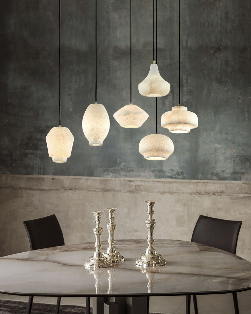 Assorted alabaster pendant lights above a round marble table with silver candlesticks