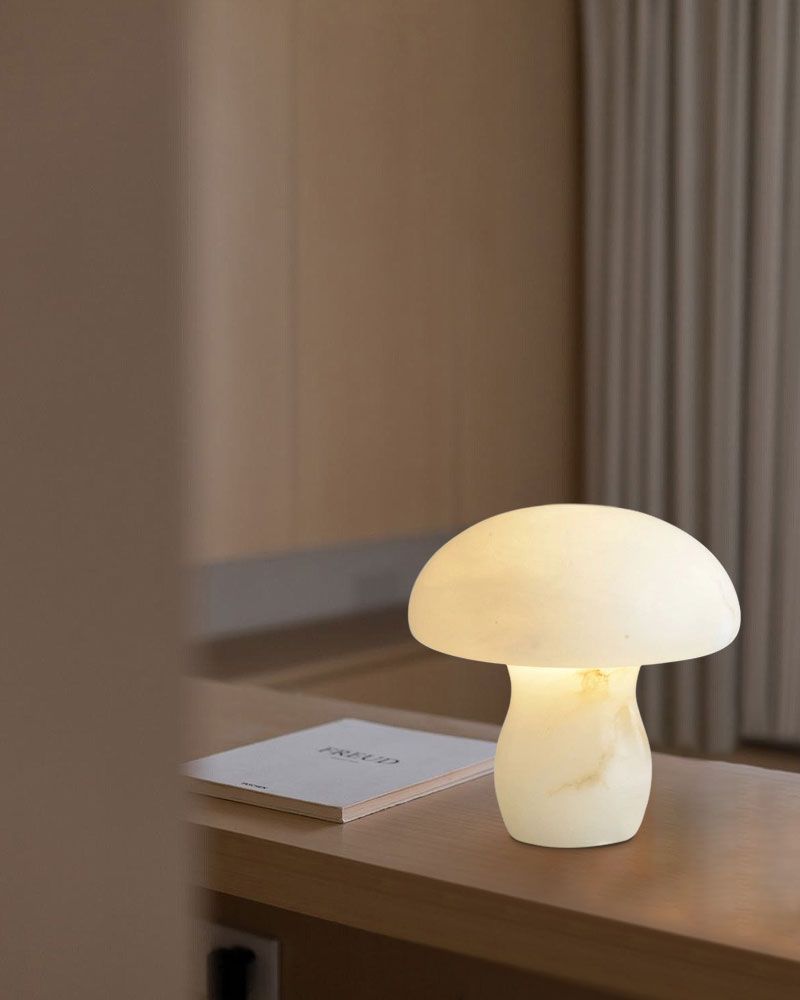 Cosy white mushroom lamp casting soft light on a wooden table with a book.