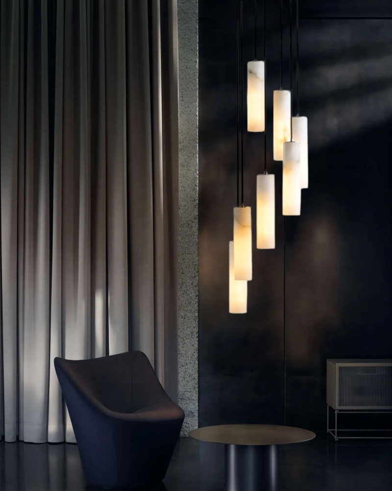 Five hanging alabaster pendant lamps illuminating a modern lounge with a sleek chair