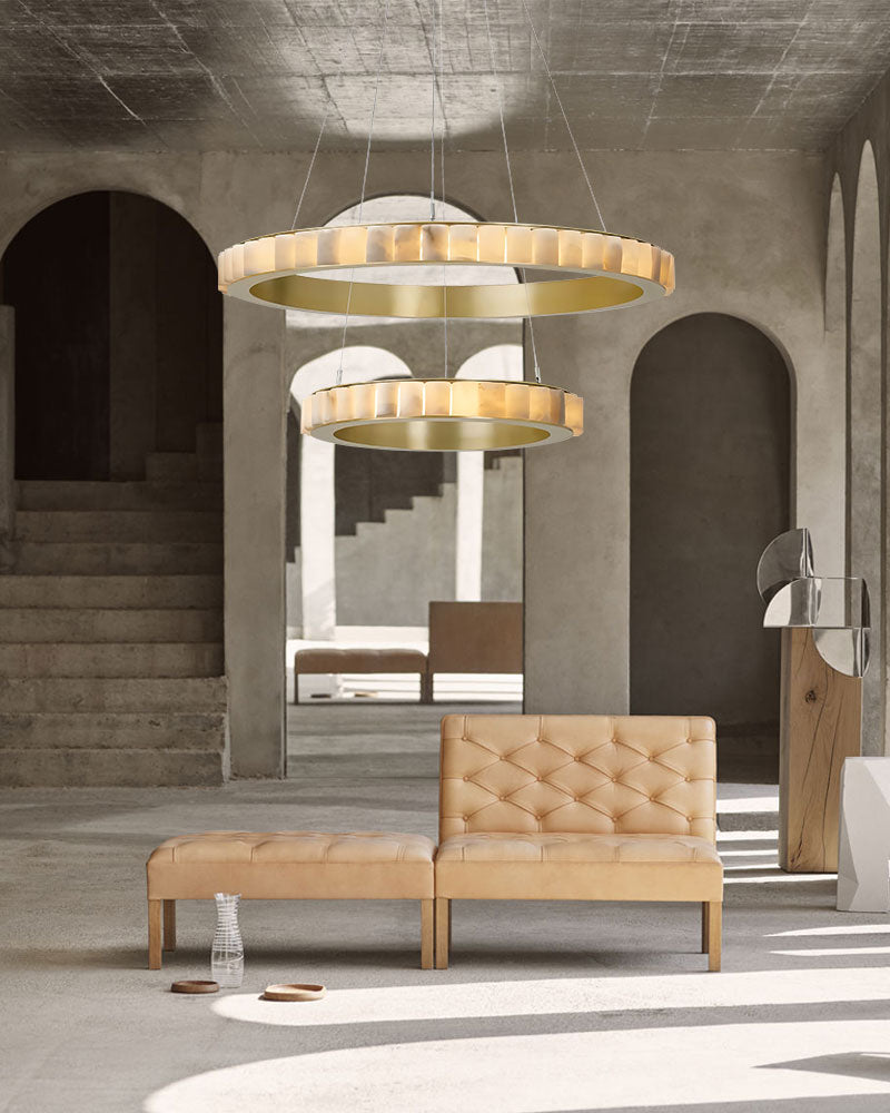 Triple chandelier with alabaster rings above sleek leather sofa in contemporary interior.