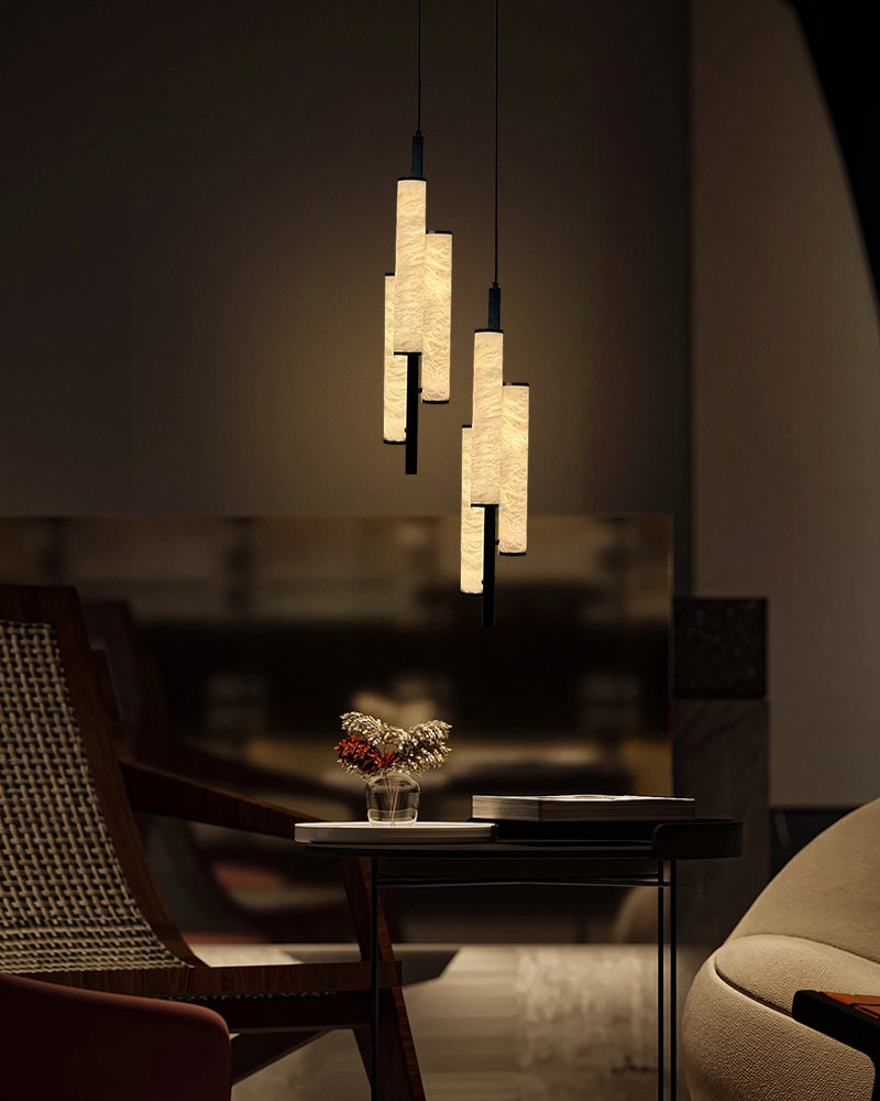 Modern alabaster pendant lights illuminating a side table with floral decor in a cozy interior.