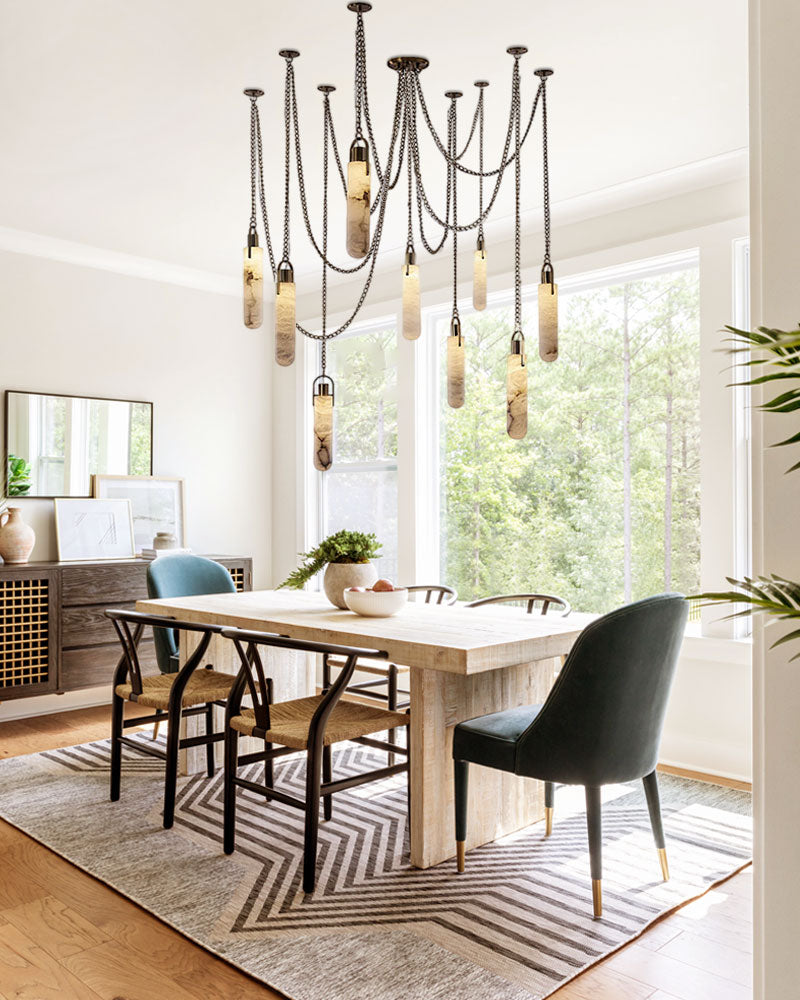 9-light brass LED cluster pendant lamp over a modern dining table in a bright room.