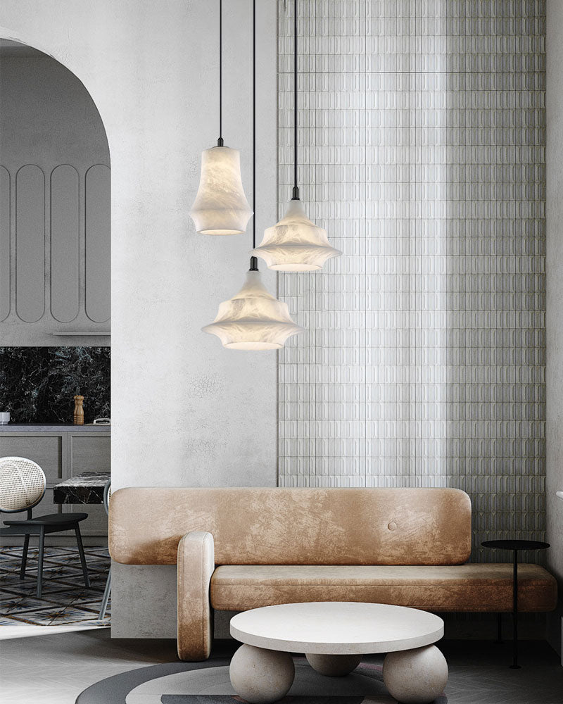 Three alabaster pendant lamps illuminating a chic living room with soft beige furnishings.