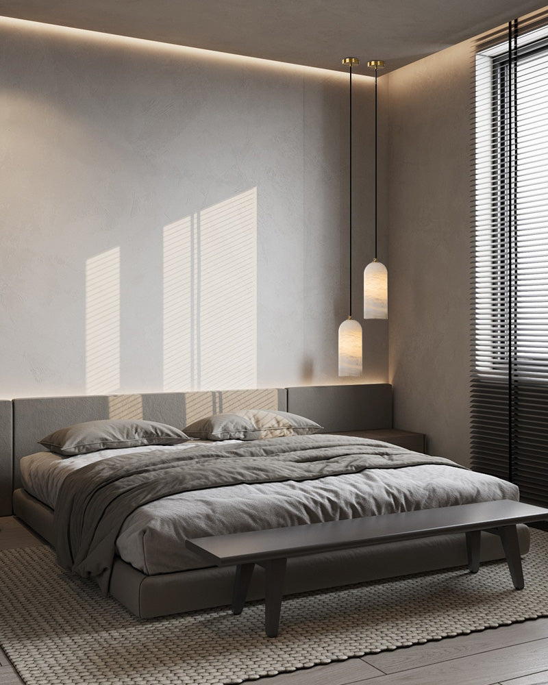 Modern bedroom featuring a gray bed, two pendant lamps, and stylish decor.