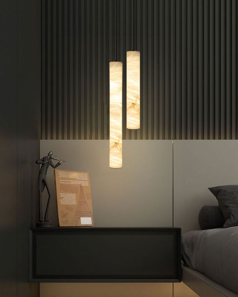Alabaster cylindrical wall lamps illuminating a modern bedroom setting.