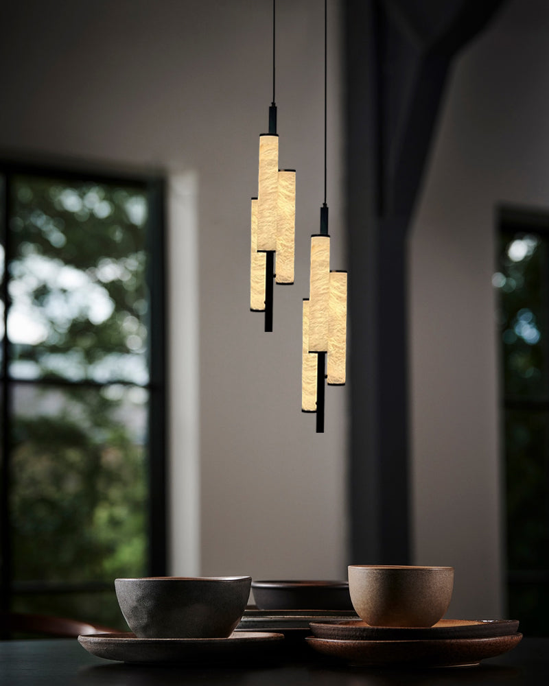 Cylindrical alabaster pendant lamps above bowls for dining room decor