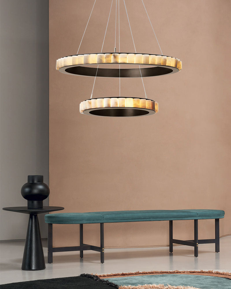 Stylish triple chandelier with alabaster rings above a minimalist bench and side table.