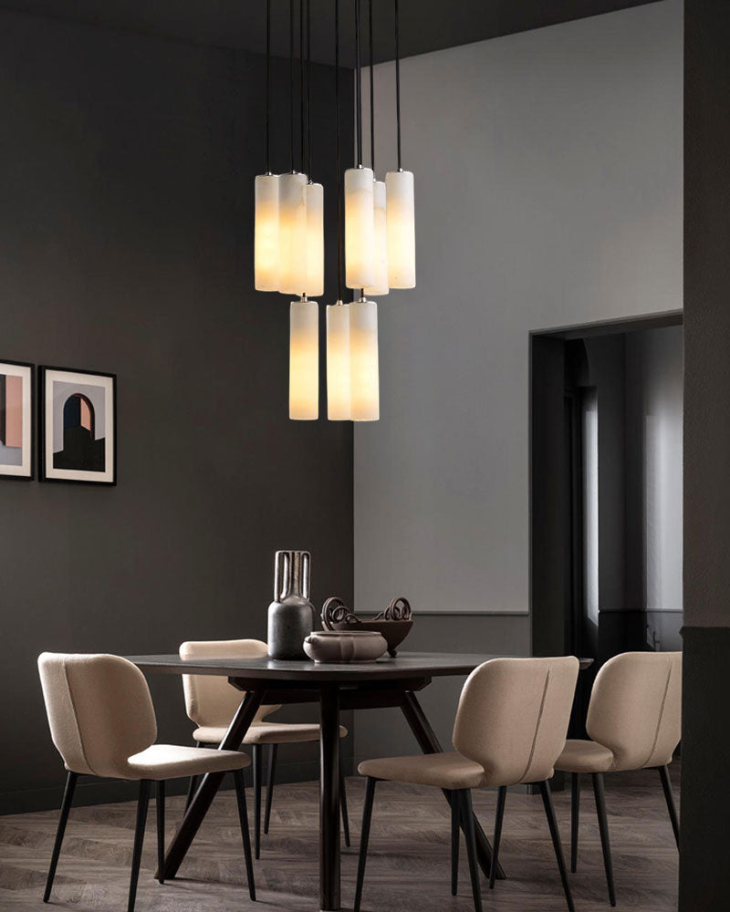 Five alabaster pendant lamps above a modern round dining table with beige chairs.