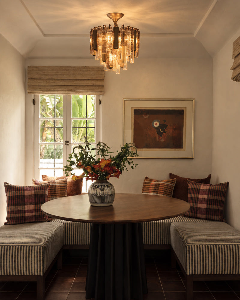 Brass flush mount ceiling light with multi-tier crystal prisms above a dining table