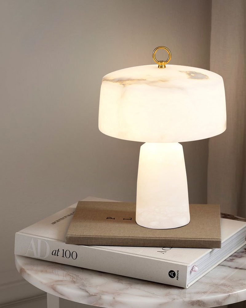 G9 natural cloud stone table lamp on stacked books atop a marble side table.