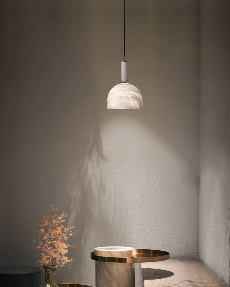 White marble pendant light illuminating a minimalist kitchen space with wooden accents.