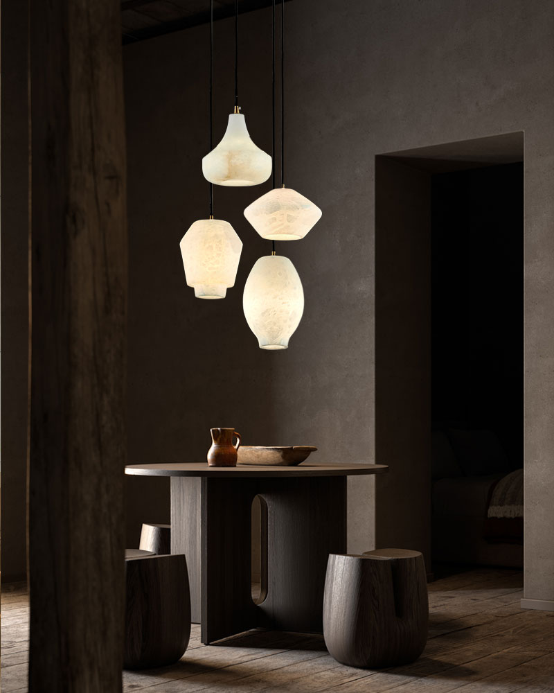 Four alabaster pendant lamps above a round wooden table in a stylish dining area.