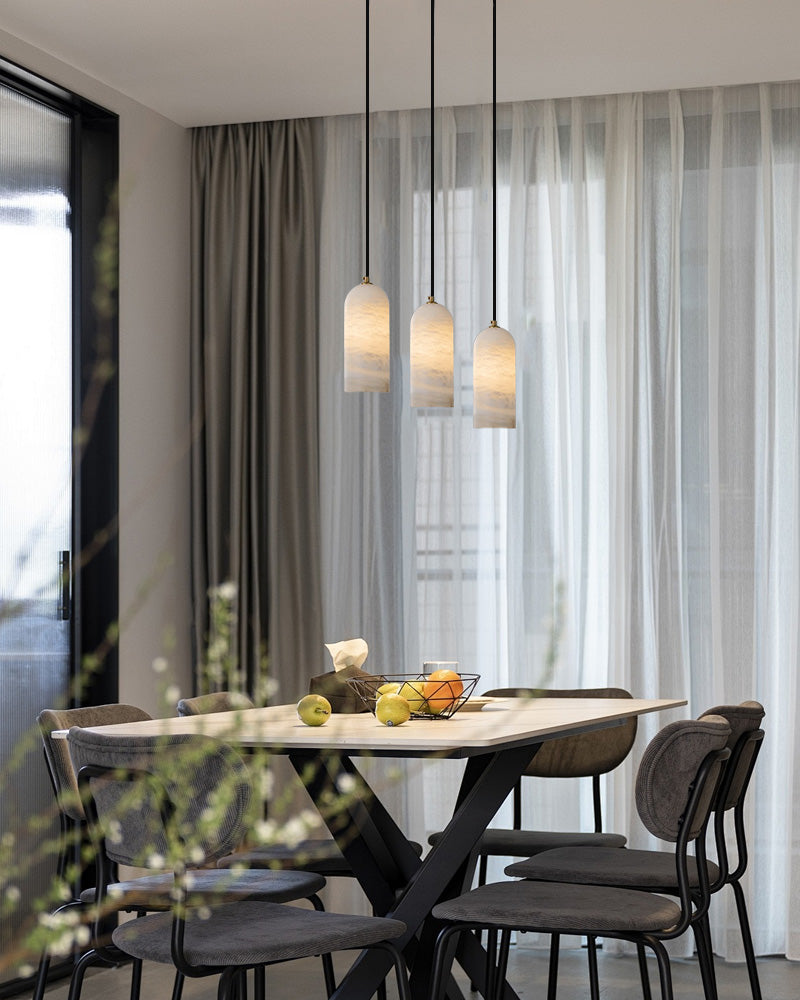 Modern dining area with white marble table and three stylish pendant lamps.