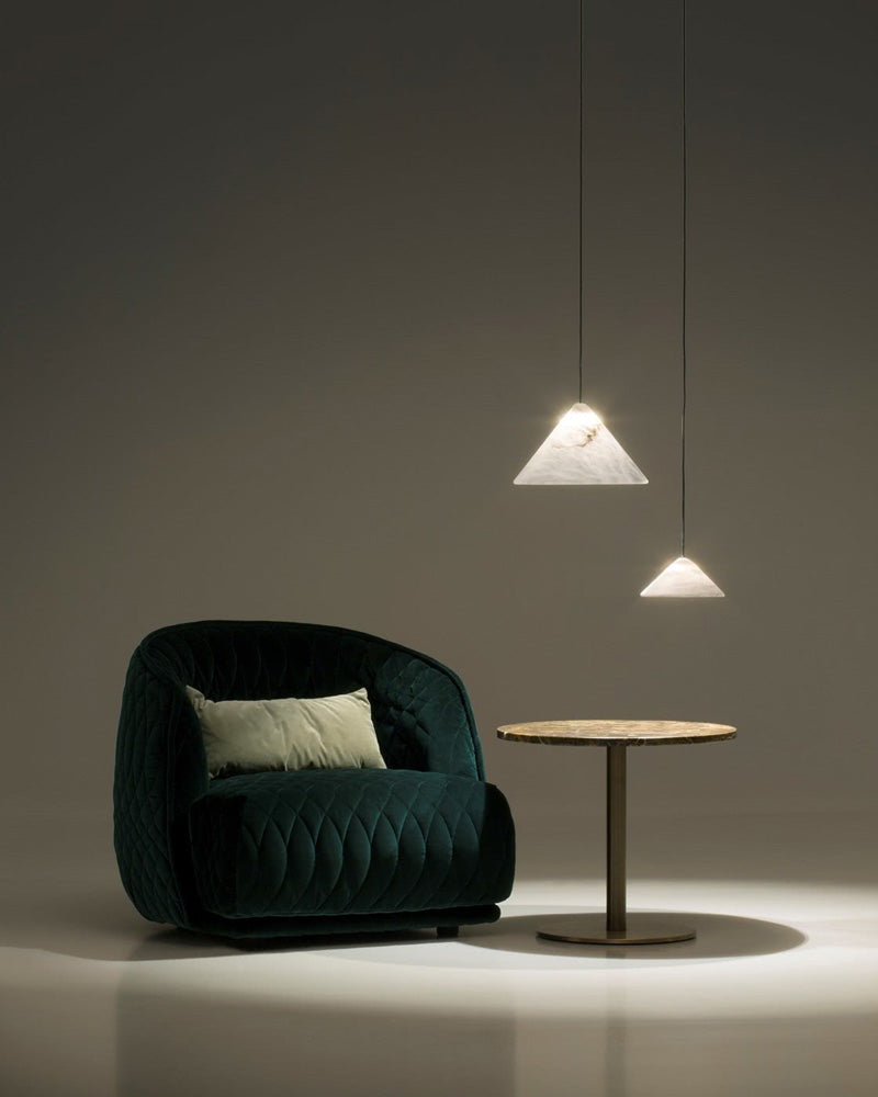 Elegant green armchair with round marble table and conical alabaster pendant lamps.