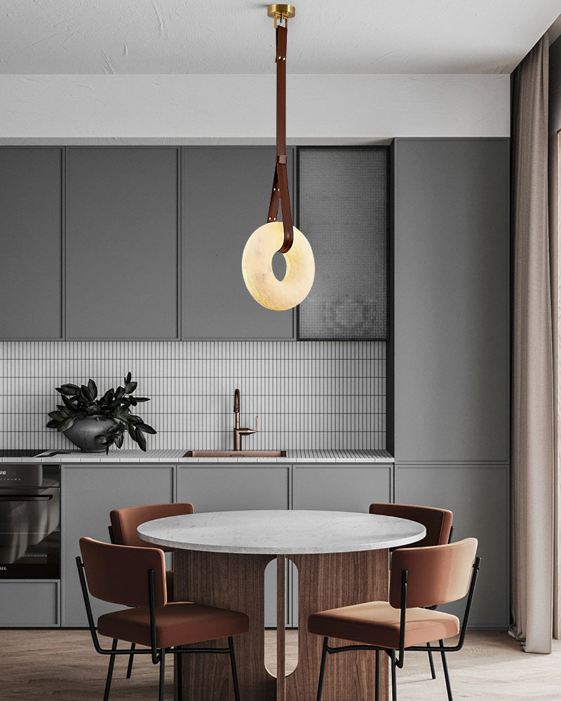 Contemporary alabaster LED pendant lamp with leather strap illuminating a round dining table.