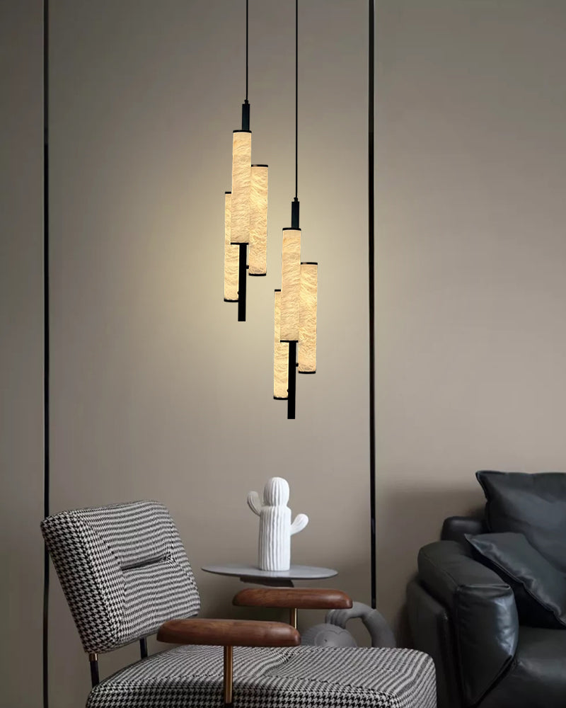 Three contemporary alabaster pendant lights above a stylish chair and table for home decor.