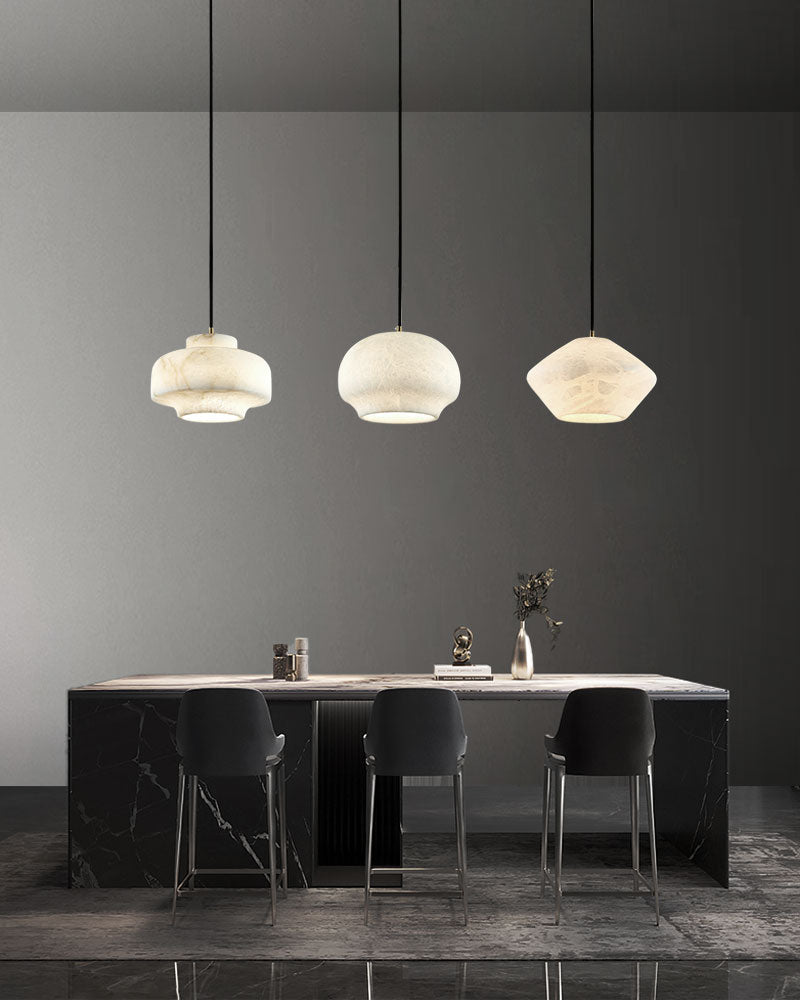 Three unique alabaster pendant lamps above sleek black bar table in modern decor.