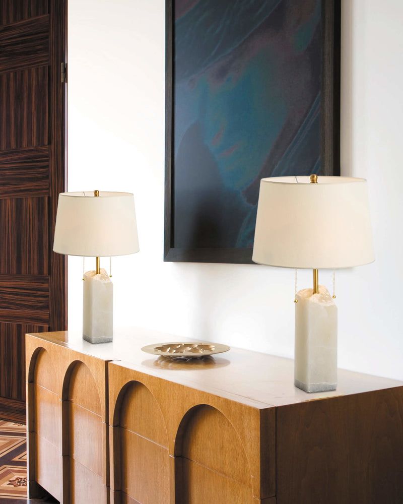 Elegant alabaster table lamps with linen shades on a wooden sideboard.